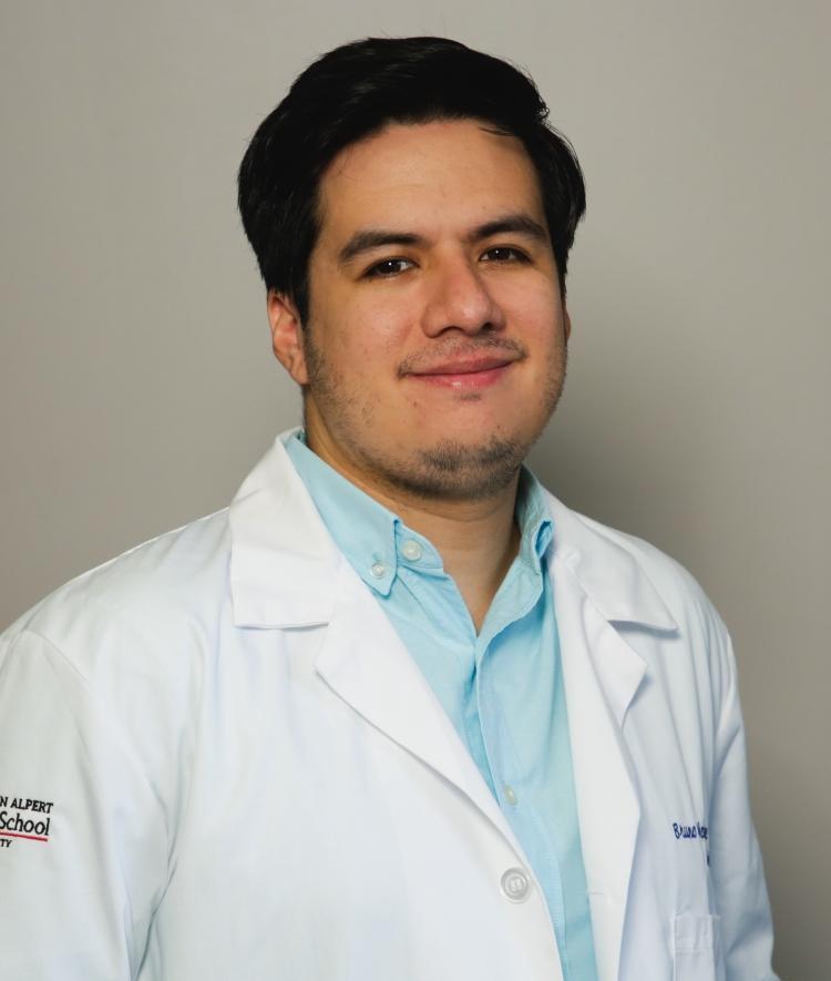 a young man with black hair wearing a doctor's white coat