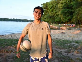 Student holds volleyball while standing in front of the lake access at Lake Campus
